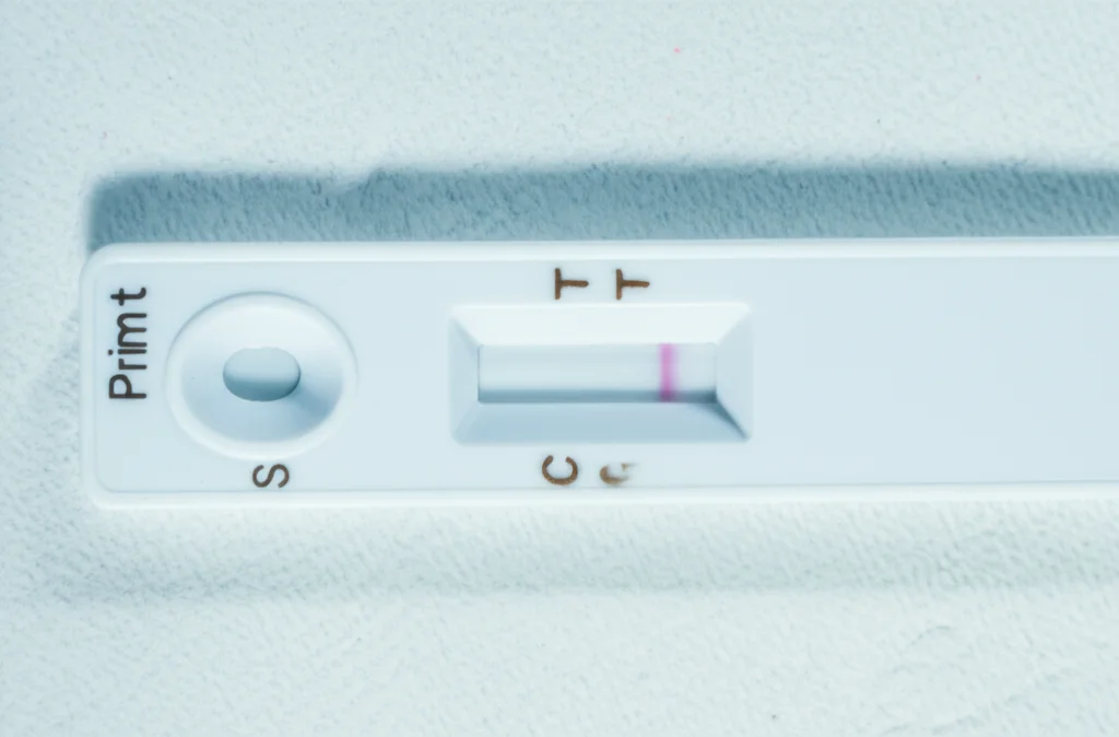 Primo piano macro di una striscia reattiva del test LF-LAM per la tubercolosi che mostra un risultato positivo, appoggiata su una superficie pulita in un ambiente clinico. Obiettivo macro 90mm, alta definizione, illuminazione laterale controllata per enfatizzare la linea del test.