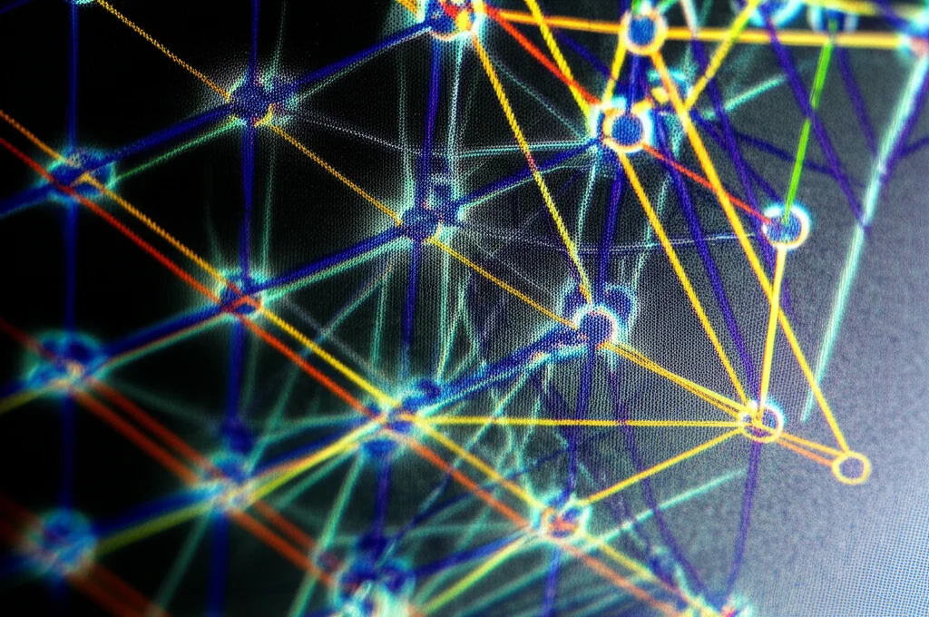 Primo piano di uno schermo di computer che mostra un grafo complesso rappresentante le connessioni tra spigoli di un ipercubo. Linee luminose indicano le 'fasi' identificate da un algoritmo. Focus preciso, illuminazione controllata, lente macro 80mm.