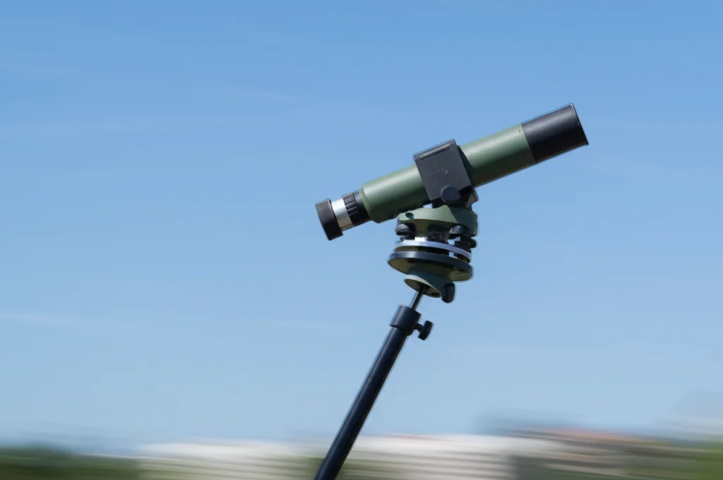 Fotografia teleobiettivo zoom (200mm) di un teodolite fotoelettrico che segue fluidamente un bersaglio aereo nel cielo sereno, effetto 'motion blur' leggero sullo sfondo per indicare il movimento, messa a fuoco precisa sul teodolite, fast shutter speed.