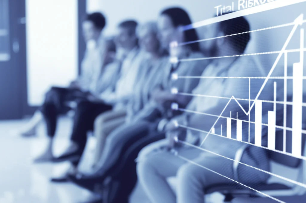 Ritratto fotografico di gruppo sfocato di pazienti diversi (età, genere) in una sala d'attesa clinica, focus nitido su un grafico medico in primo piano che mostra statistiche di rischio. Obiettivo prime 35mm, profondità di campo ridotta, toni duotone blu e grigio.