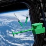 Immagine fotorealistica del sistema MiniFix completo, stampato in 3D con materiale GreenTEC Pro biodegradabile verde, fluttuante in un ambiente di microgravità stilizzato con la Terra vista da un finestrino della ISS sullo sfondo. Obiettivo 35mm, profondità di campo che sfoca leggermente lo sfondo terrestre, illuminazione drammatica laterale che evidenzia la texture del materiale stampato e i dettagli delle siringhe interne.