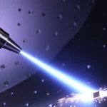Immagine fotorealistica, obiettivo zoom teleobiettivo 150mm, che cattura l'intensa interazione di un getto di plasma d'aria incandescente (caldo blu/bianco) che colpisce un campione di lega di titanio Ti-6Al-4V all'interno di una camera a vuoto. Potrebbero essere visibili scintille o particelle incandescenti. Tracciamento dell'azione, velocità dell'otturatore elevata per congelare il bordo del plasma.