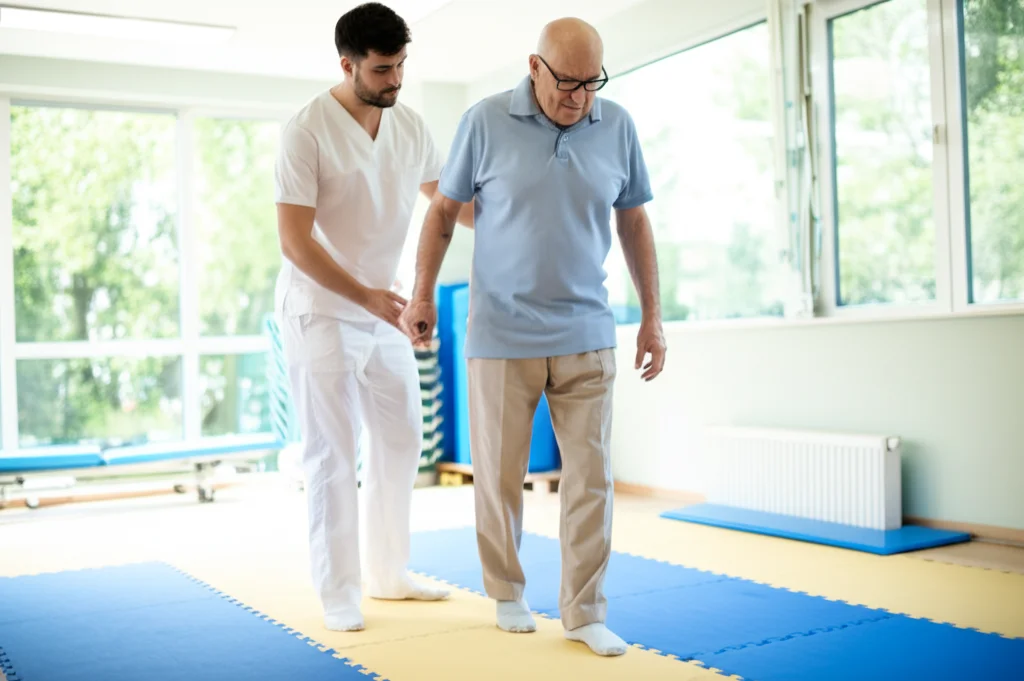 Paziente anziano con emiplegia esegue esercizi di equilibrio (come stare su una gamba) assistito da un fisioterapista in una palestra riabilitativa luminosa e moderna, obiettivo 35mm, profondità di campo, luce naturale che entra dalle finestre.
