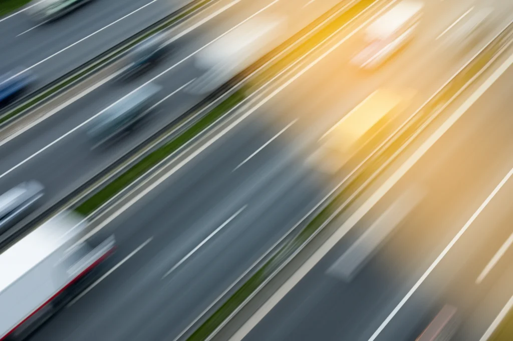 Foto aerea catturata da un drone in rapido movimento sopra un'autostrada trafficata, teleobiettivo zoom 200mm, alta velocità dell'otturatore per congelare il movimento dei veicoli, tracciamento dell'azione sui veicoli per evidenziare la sfida della super-risoluzione in scenari dinamici.