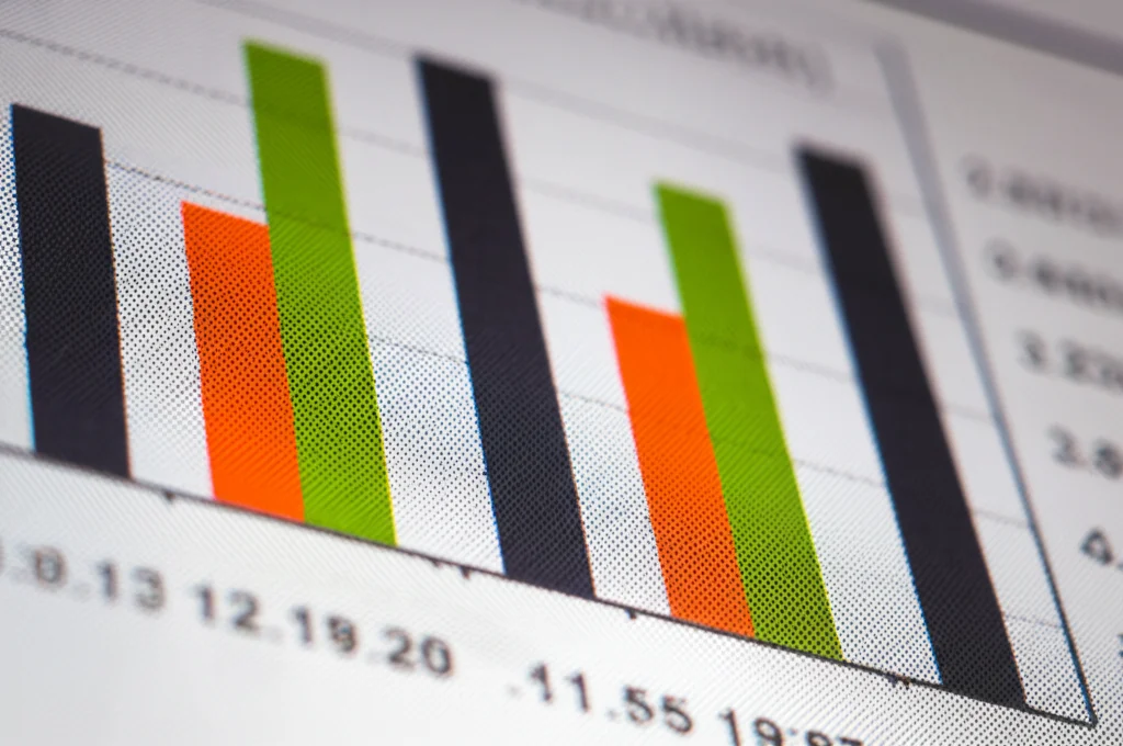 Immagine macro di un grafico a barre colorate su uno schermo di computer o su carta stampata, con numeri e etichette sfocate sullo sfondo. Focus preciso sulle barre che rappresentano dati statistici. Stile: macro lens, 85mm, high detail, precise focusing, controlled lighting, colori vivaci ma professionali, che simboleggia l'analisi rigorosa dei dati dello studio.