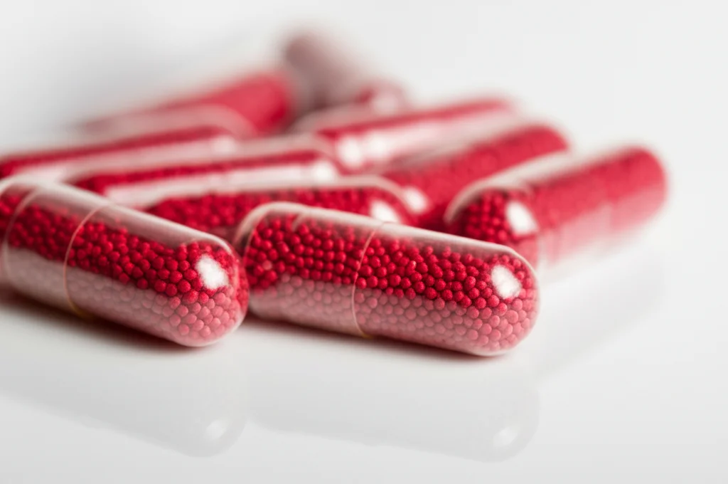 Primo piano macro di capsule di integratore di lattoferrina su una superficie bianca e pulita, illuminazione da studio controllata per massima nitidezza, obiettivo macro 90mm, alta definizione.