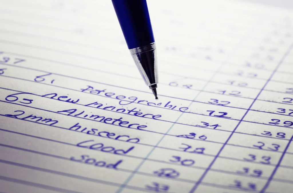 Fotografia macro di una penna sospesa sopra un diario alimentare aperto, con numeri e nomi di cibi scritti a mano. Luce laterale morbida che crea ombre delicate, obiettivo 60mm macro, alta definizione dei dettagli della carta e dell'inchiostro.