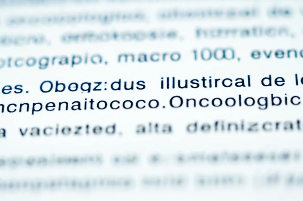 Fotografia macro di un foglietto illustrativo di un farmaco oncologico, con testo piccolo e complesso. Obiettivo macro 100mm, alta definizione, illuminazione controllata per evidenziare la difficoltà di lettura.