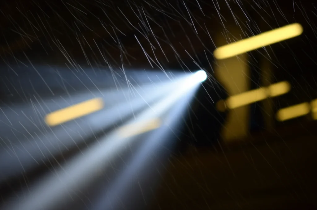 Fotografia macro di particelle di polvere industriale sospese in un raggio di luce all'interno di una fabbrica poco illuminata, obiettivo macro 90mm, alta definizione, illuminazione controllata per evidenziare le particelle.