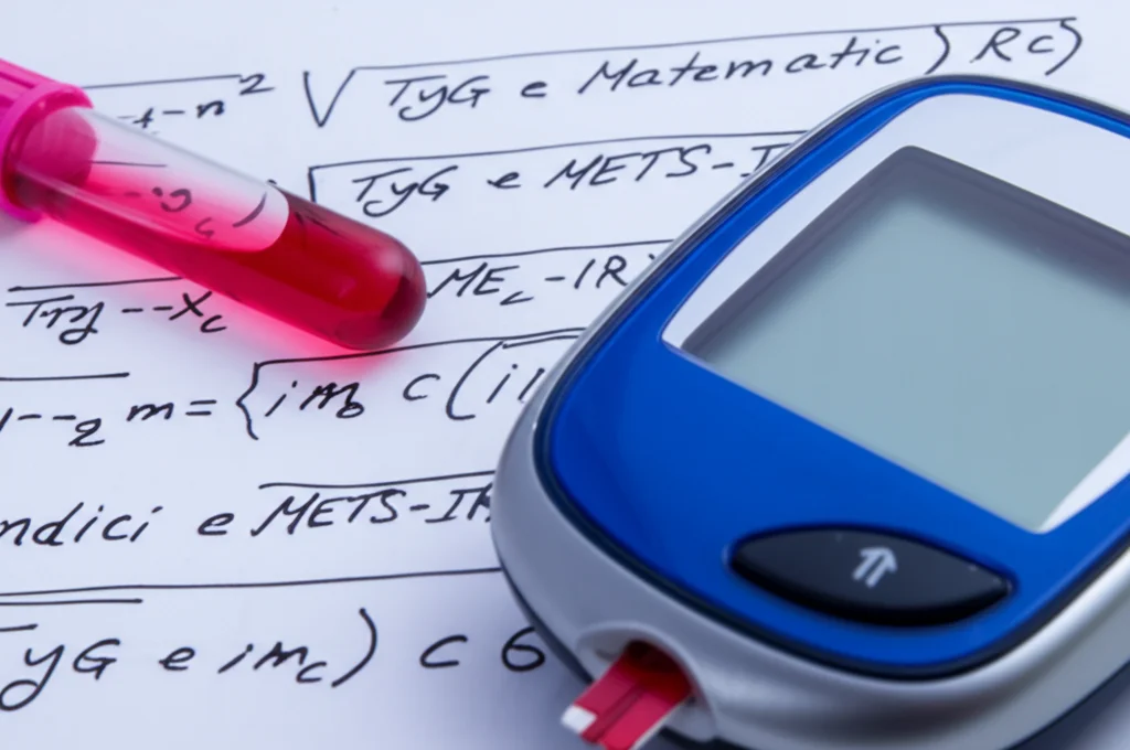 Fotografia still life, lente macro 100mm, di una provetta di sangue accanto a un glucometro e un foglio con formule matematiche stilizzate rappresentanti gli indici TyG e METS-IR, illuminazione da studio precisa, alto dettaglio.