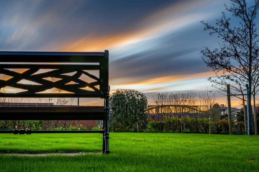 Scena grandangolare di un giardino sereno con una panchina vuota al tramonto, evocando momenti di pace e piacevoli attività all'aperto per pazienti con Alzheimer, obiettivo 18mm, lunga esposizione per nuvole soffuse.