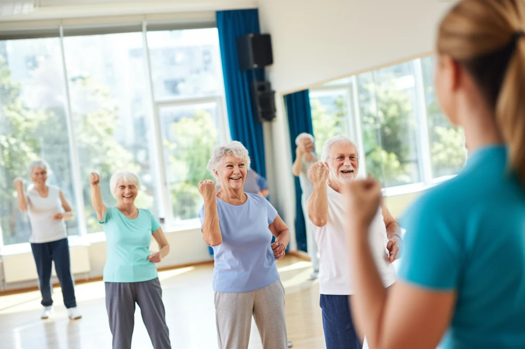 Un gruppo eterogeneo di anziani sorridenti che partecipano a una lezione di aerobica leggera in una palestra luminosa, guidati da un istruttore. Obiettivo prime 35mm, luce controllata, profondità di campo per mettere a fuoco il gruppo ma sfocare leggermente lo sfondo.