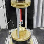 Levitatore acustico sferico con 35 trasduttori in funzione all'interno del nefelometro polare del CoDuLab, una sfera di vetro di 1.5mm levita stabilmente al centro, illuminata da un fascio laser rosso visibile. L'apparato è montato su un banco ottico in un laboratorio scientifico. Fotografia scientifica, obiettivo macro 90mm, alta definizione, illuminazione controllata da laboratorio, profondità di campo ridotta per focalizzare sulla sfera levitante.