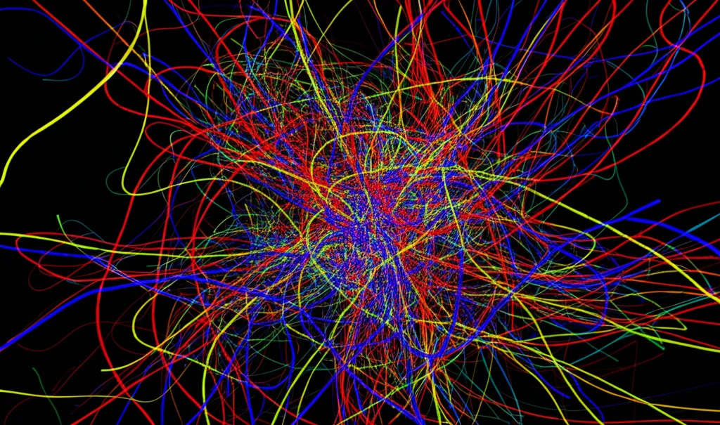 Simulazione numerica astratta di turbolenza quantistica, mostrando un groviglio complesso di linee di vortice colorate (blu, rosse, verdi) che interagiscono e si riconnettono in un volume cubico. Stile wide-angle 15mm, colori vibranti, sensazione di movimento caotico ma strutturato, lunga esposizione simulata per mostrare le traiettorie.
