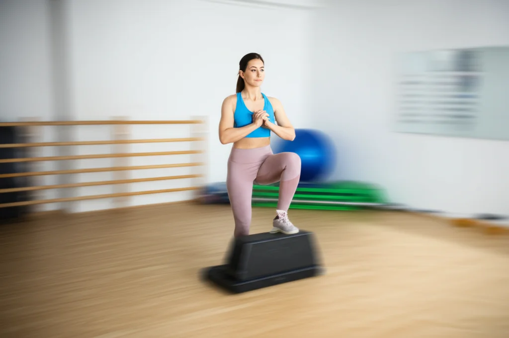 Tennista donna che esegue un test di affondo (weight-bearing lunge) per valutare la mobilità della caviglia e la stabilità del ginocchio su una pedana in palestra. Fotografia sportiva in movimento, teleobiettivo zoom 100mm, alta velocità dell'otturatore, messa a fuoco precisa sulla postura e l'allineamento.