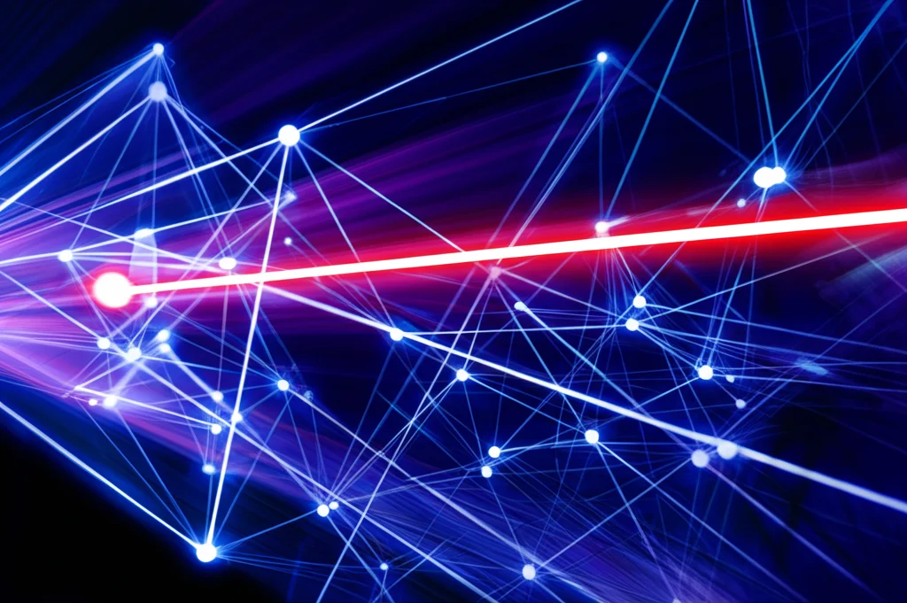 Immagine astratta che rappresenta una rete complessa di connessioni digitali luminose su sfondo scuro, con alcune linee rosse che simboleggiano conflitti o aggressioni. Effetto motion blur leggero, colori vibranti blu, viola e rosso. #cyberbullismo #rete #connessioni #conflitto #digitale