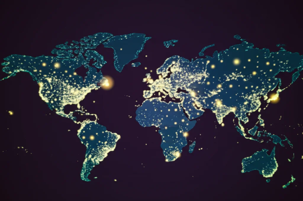 Mappa del mondo stilizzata con punti luminosi che evidenziano i principali centri di ricerca (UK, Italia, USA, Cina, Finlandia) sugli ecosistemi imprenditoriali. Stile infografica fotorealistica, obiettivo grandangolare 24mm, messa a fuoco nitida, colori vivaci su sfondo scuro.