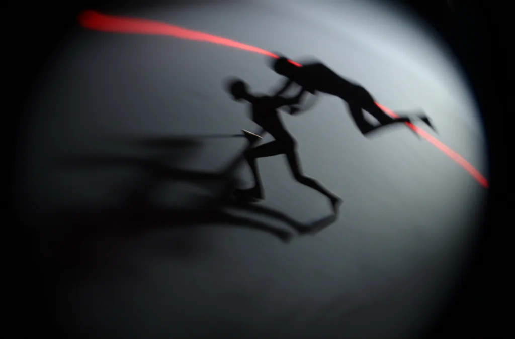 Fotografia concettuale wide-angle 20mm che mostra due figure stilizzate, una aggrappata disperatamente all'altra che cerca di allontanarsi, su uno sfondo sfocato che simboleggia il conflitto interiore ed esteriore. Illuminazione drammatica, long exposure per creare un senso di movimento bloccato.