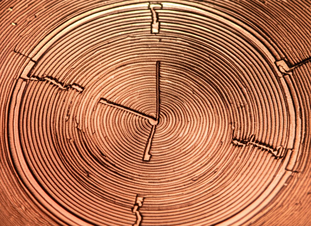 Fotografia macro, 100mm, di un prototipo di metamateriale DNG fabbricato su substrato Rogers RT 5880, mostrando i dettagli dei risonatori concentrici in rame lucido e degli intagli. Illuminazione da studio precisa, alta definizione, focus sui dettagli geometrici.