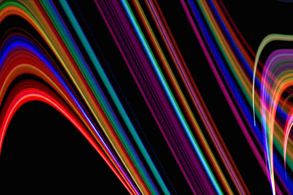 Visualizzazione astratta di onde sinusoidali colorate che si intrecciano su uno sfondo scuro, rappresentante l'analisi wavelet. Alcune onde (AOD) sono in fase con altre (meteo), altre in anti-fase. Utilizzare un obiettivo macro, focale 90mm, per catturare i dettagli intricati delle onde sovrapposte con alta precisione e illuminazione drammatica per creare contrasto.