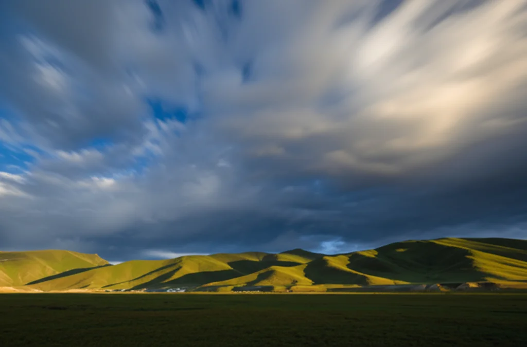 Paesaggio grandangolare di una regione montuosa della Cina, forse l'altopiano del Qinghai-Tibet, con nuvole cariche di pioggia che si muovono lentamente nel cielo, luce del tardo pomeriggio che crea ombre lunghe, lunga esposizione per rendere le nuvole setose, obiettivo grandangolare 18mm, messa a fuoco nitida sull'intero paesaggio.