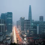 Fotografia a livello stradale di Seoul in una giornata invernale nebbiosa, con grattacieli parzialmente oscurati dallo smog e luci della città soffuse. Obiettivo prime, 35mm, profondità di campo, colori desaturati per enfatizzare l'inquinamento atmosferico e l'impatto sulla vita urbana.