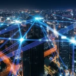 Immagine grandangolare 10mm di un paesaggio urbano futuristico di notte, con scie luminose blu e viola che rappresentano i segnali 5G che si interconnettono tra gli edifici e convergono su specifici punti luminosi, simboleggiando la localizzazione precisa in un ambiente complesso. Lunga esposizione, messa a fuoco nitida.