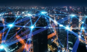 Immagine grandangolare 10mm di un paesaggio urbano futuristico di notte, con scie luminose blu e viola che rappresentano i segnali 5G che si interconnettono tra gli edifici e convergono su specifici punti luminosi, simboleggiando la localizzazione precisa in un ambiente complesso. Lunga esposizione, messa a fuoco nitida.