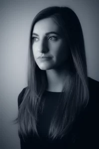 Immagine simbolica di una donna che riflette sulle scelte terapeutiche per il cancro al seno metastatico, con un effetto di luce soffusa che illumina il suo volto pensieroso, lente da ritratto 50mm, duotone blu e grigio per un'atmosfera introspettiva.