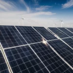 Wide-angle landscape, 10mm lens, expansive solar farm with rows of photovoltaic tracking supports tilted at different angles, strong wind blowing, motion blur on wind turbines in the distance, sharp focus on the foreground panels.