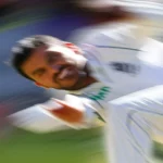 Photorealistic image of a cricket bowler delivering a ball, showing the strain on the body, telephoto zoom, 250mm, fast shutter speed, motion blur on the ball, action tracking.