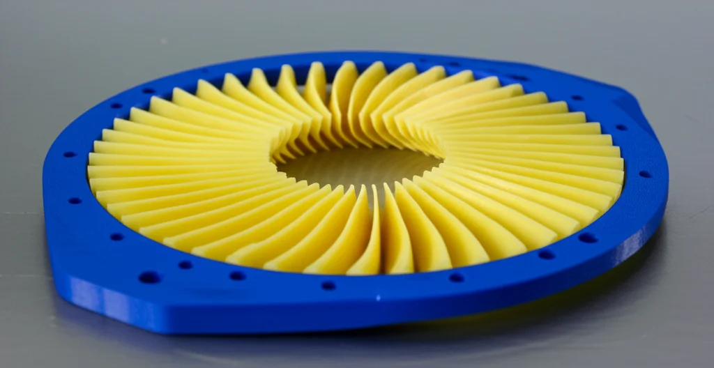 Fotografia still life di una valvola deviatrice rotante stampata in 4D, realizzata in PLA, che cambia forma sotto stimolo termico in un ambiente di laboratorio pulito. Obiettivo macro 90mm, illuminazione da studio controllata per evidenziare i dettagli della struttura e la trasformazione, alta definizione.