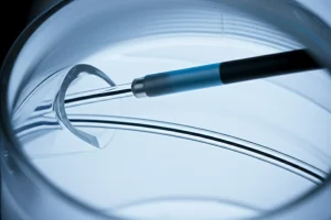 Un'immagine macro altamente dettagliata di un catetere IVUS (ecografia intravascolare) che viene guidato attraverso un modello trasparente di un seno venoso cerebrale, con un focus preciso sulla punta del trasduttore. Illuminazione controllata per evidenziare la tecnologia. Lente macro, 90mm.