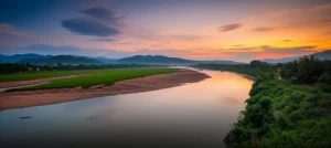 Immagine fotorealistica di un'ampia ansa del fiume Nan, Thailandia settentrionale, al tramonto, con terrazze fluviali e vegetazione lussureggiante visibili. Ripresa con obiettivo grandangolare da 14mm, lunga esposizione per rendere l'acqua setosa, cielo con nuvole striate, colori caldi e intensi, messa a fuoco nitida su tutto il paesaggio, evidenziando la potenza e la bellezza del sistema fluviale.