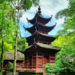 Wide-angle landscape photo, 10mm focal length, sharp focus, showing a historical temple nestled within a lush forest, illustrating the blend of nature and culture at a popular heritage site facing visitor density challenges.