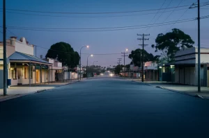 Immagine simbolica dell'impatto della deindustrializzazione e del COVID-19 su una comunità australiana: una strada deserta in una cittadina industriale al crepuscolo, con le luci delle case accese ma poche persone visibili. Wide-angle lens, 20mm, long exposure, atmosfera malinconica ma con un barlume di speranza, colori freddi con accenti caldi dalle finestre.