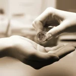 Immagine simbolica del divario salariale di genere: due mani, una maschile e una femminile, che tengono monete di valore diverso su uno sfondo sfocato di un ufficio del Nord Italia. Macro lens 100mm, high detail, controlled lighting, duotone seppia e grigio per un effetto serio ma speranzoso.