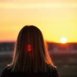 Una persona che guarda con speranza verso un orizzonte luminoso, simboleggiando il sollievo dall'emicrania cronica e dall'abuso di farmaci grazie a nuove terapie. Luce calda del tramonto, obiettivo 35mm, profondità di campo, colori caldi e rassicuranti.