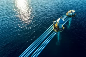 Impianto OTEC futuristico in mare aperto, con tubi che scendono nelle profondità blu scuro, luce solare che si riflette sulla superficie dell'acqua, teleobiettivo, 200mm, alta definizione, luce del tardo pomeriggio, per illustrare la tecnologia OTEC e il suo potenziale energetico.