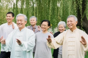 A diverse group of smiling elderly Chinese individuals participating in a gentle outdoor Tai Chi class, with a backdrop of a serene park with willow trees. Prime lens, 35mm, depth of field, capturing a sense of community, peace, and active healthy aging.