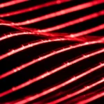 Close-up estremo, lente macro 100mm, di un tessuto flessibile con un display OLED rosso acceso integrato che mostra un motivo luminoso. Il tessuto è leggermente piegato per evidenziare la flessibilità. Illuminazione drammatica e controllata per far risaltare la luce dell'OLED e la texture del tessuto. Alta definizione, messa a fuoco precisa sull'interfaccia tra OLED e tessuto.