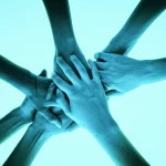 Immagine concettuale di una rete di mani che si sostengono a vicenda, simboleggiando il supporto tra pari e la comunità nella riduzione del danno e nel percorso di recupero. Prime lens, 24mm, duotone blu e verde, forte impatto emotivo.