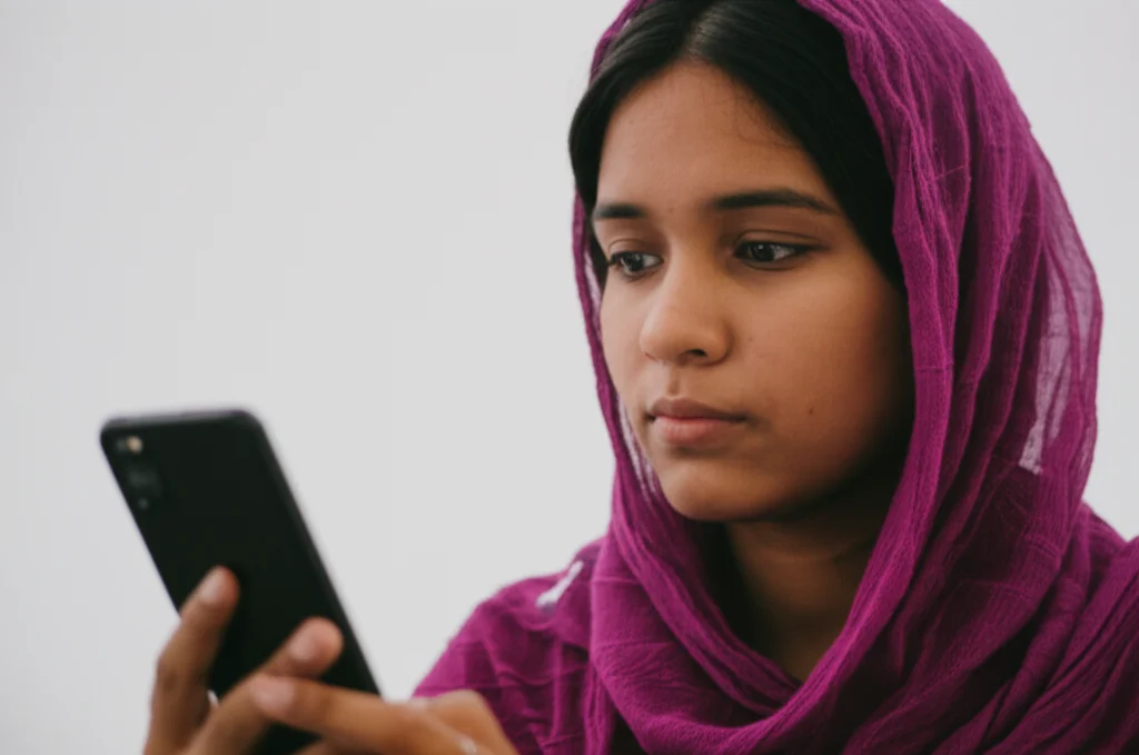 Portrait of a person in Bangladesh looking at a smartphone, 35mm portrait, depth of field, suggesting information access via social media.