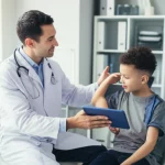 Un medico pediatra reumatologo mostra a un bambino e al suo genitore come utilizzare un'applicazione sanitaria digitale su un tablet in uno studio medico luminoso e accogliente. Fotografia ritratto, obiettivo 35mm, colori caldi, profondità di campo per sfocare leggermente lo sfondo.