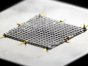 Immagine fotorealistica di un campione di grafene ad angolo magico (MATBG) su un substrato, con elettrodi visibili per misurazioni. Macro lens, 100mm, high detail, precise focusing, controlled lighting per evidenziare la natura 2D del materiale e le connessioni del dispositivo utilizzato per studiare la superconduttività.