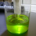 Immagine macro, obiettivo 90mm, di una cuvetta di quarzo contenente una soluzione di dutasteride che emette una debole fluorescenza bluastra sotto eccitazione UV, all'interno di uno spettrofluorimetro. Illuminazione controllata da laboratorio, alta definizione, messa a fuoco precisa sulla cuvetta, sfondo scuro per esaltare la fluorescenza.