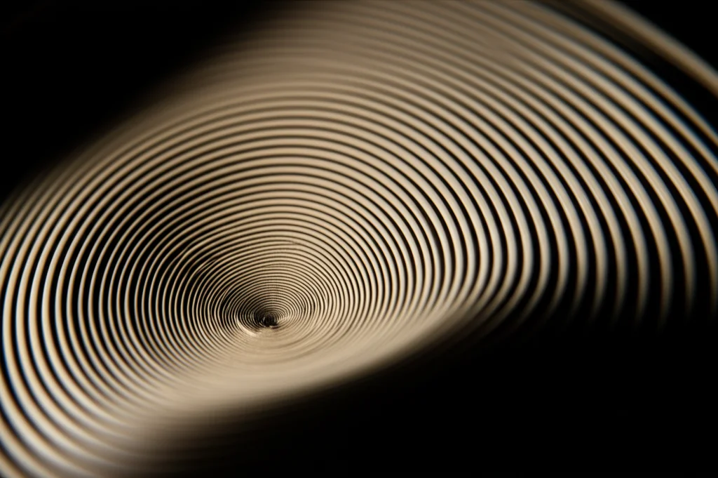 Un pezzo di materiale viscoelastico avanzato, come poliuretano o silicone, che viene compresso o deformato visibilmente da una forza esterna stilizzata (non una vera esplosione), evidenziando la sua capacità di assorbire l'impatto. Macro lens, 80mm, high detail, controlled lighting, per mostrare la texture e la deformazione del materiale sotto stress, con un leggero effetto di motion blur sulla forza impattante per suggerire dinamicità.