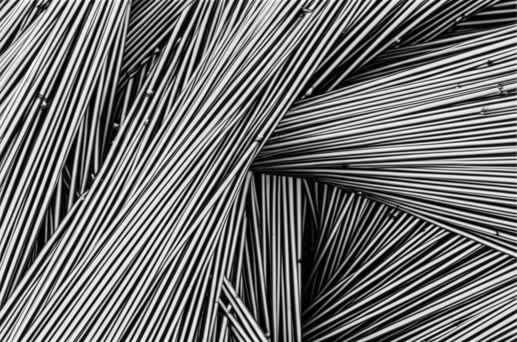 Immagine fotorealistica al microscopio elettronico di una rete complessa di dislocazioni all'interno di un metallo cristallino (tungsteno), illuminazione drammatica laterale, high detail, macro lens 100mm, che evidenzia le imperfezioni su scala atomica e la struttura BCC.