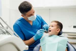 Portrait photography, 35mm lens, depth of field, che cattura un dentista pediatrico mentre spiega con dolcezza una procedura dentale a un giovane bambino attento, in una clinica dentistica moderna e luminosa, enfatizzando la cura e la tecnologia avanzata.