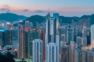 Immagine fotorealistica di un iconico edificio industriale di Hong Kong, riqualificato e integrato nel moderno skyline della città. Obiettivo grandangolare 20mm, fotografia architettonica al tramonto con lunga esposizione per enfatizzare le luci della città e la maestosità della struttura, dettagli nitidi.